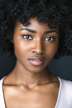 a close up of a person with an afro hair style and blue eyeshadow