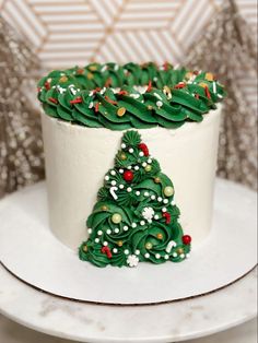 a white cake with green frosting decorated like a christmas tree on top, sitting on a plate