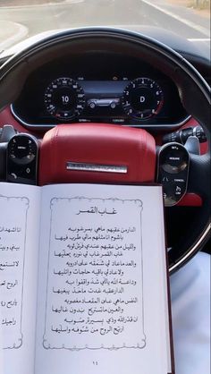 an open book sitting in the middle of a car's steering wheel, with arabic writing on it