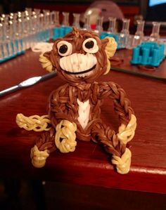 a monkey made out of pasta sitting on top of a wooden table next to glasses