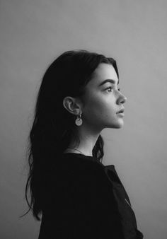 a black and white photo of a woman with long dark hair wearing earrings