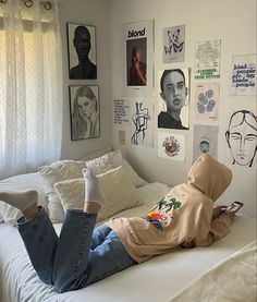 a person laying on top of a white bed in a room with pictures hanging on the wall