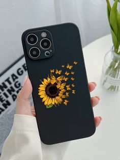 a person holding up a phone case with a sunflower and butterflies on it