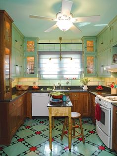 a kitchen with green walls and flooring has an old fashioned ceiling fan above the stove