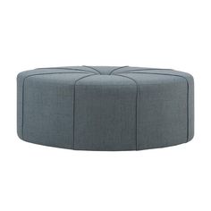 a grey ottoman that is sitting on top of a white floor and it's made out of fabric