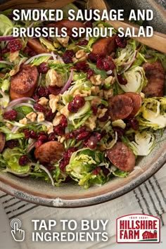 a bowl filled with sausage and brussels sprout salad on top of a table