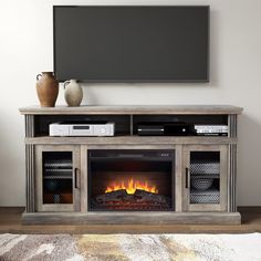 an entertainment center with a fire place and television on it's stand in front of a flat screen tv