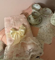 a table topped with lots of pink and white dishes next to a cup filled with saucers