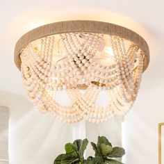 a white chandelier hanging from the ceiling in a room with potted plants