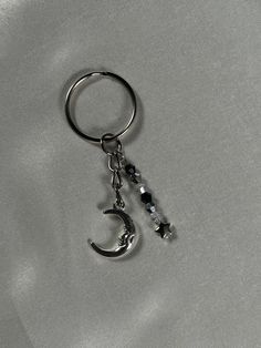 A handmade keyring with a celestial theme. Perfect for a gift or a treat to yourself!! The keychain features a moon charm on one chain. On an additional chain - an ombre bead effect, from black, to silver, to clear, with a star on the bottom to complement the moon and to bring together the nightfall theme. Black Jewelry With Moon Charm For Festivals, Moon Charm Dangle Jewelry Gift, Metal Moon Charm Dangle Jewelry, Mystical Black Jewelry With Moon Charm, Moon Keychain, Celestial Theme, Pant Chains, Silver Nail, Accessories Diy Jewelry