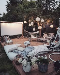 an outdoor movie is set up in the backyard with chairs, lights and blankets on it