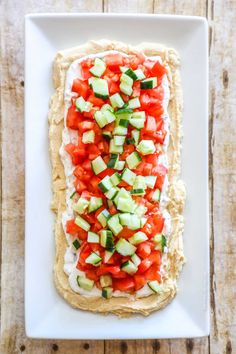 a white plate topped with hummus and cucumbers