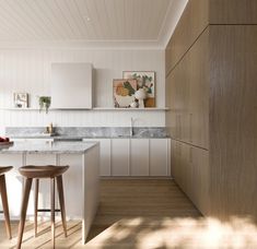 a kitchen with two stools next to an island