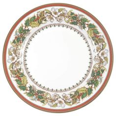 a white plate with holly and berries on the rim, decorated with red trimmings