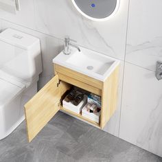 a white toilet sitting next to a bathroom sink under a mirror on top of a wooden cabinet