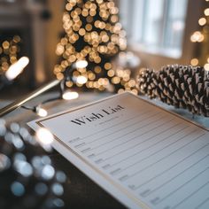 a wish list sitting on top of a table next to a pine cone and christmas tree