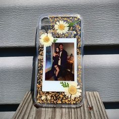 a cell phone case with flowers and a photo on the back is sitting on a wooden table