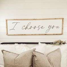 a bed with two pillows and a sign that says i choose you