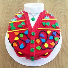 a red cake decorated with colorful decorations on top of a white plate and wooden table