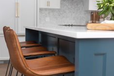 two brown chairs sitting on top of a counter next to a vase filled with flowers