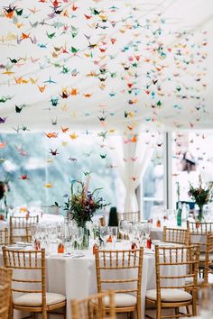 a room filled with lots of tables and chairs covered in paper cranes hanging from the ceiling