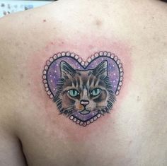 a close up of a person's chest with a cat tattoo on the back