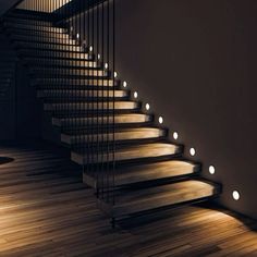 some stairs with lights on them in a dark room by the wall and wood floor