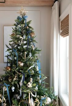 a decorated christmas tree with blue ribbon and ornaments