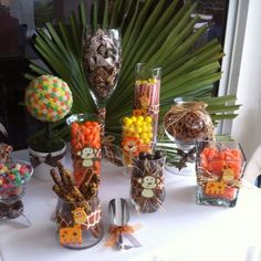 a table topped with lots of candy and candies next to a palm leaf filled vase