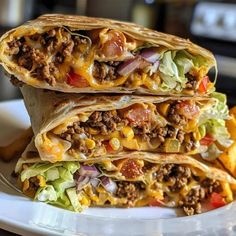 three burritos stacked on top of each other on a white plate with a fork