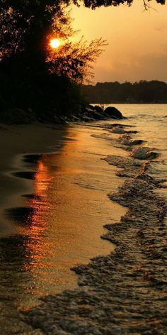 the sun is setting over the water at the beach with waves coming in to shore