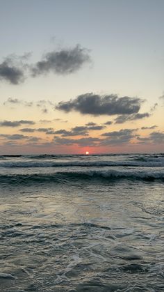 the sun is setting over the ocean with waves