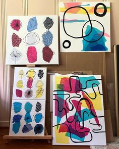 three canvases with different designs on them in front of a wall and a door