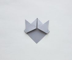 an origami flower on a white wall with the corner cut out to look like it is folded