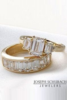 two gold rings with baguettes and diamonds on them sitting on a white cloth