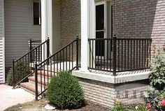 the front porch of a brick apartment with wrought iron railings and flower boxes on either side