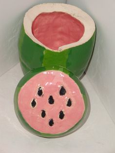 a green and pink vase sitting on top of a white table