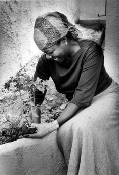 a black and white photo of a woman sitting on a ledge with flowers in her hand