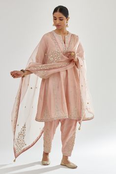 Pink silk chanderi short kalidar kurta with zari bootis, dori embroidered neckline and contrast bead work. Paired with narrow salwar in dori, zari and gota flower embroidered bootas and dupatta.
Components: 3
Pattern: Embroidery
Type Of Work: Zari, dori, gota, aari, bead
Neckline: Notched
Sleeve Type: Three quarter
Fabric: Kurta and Salwar: Silk Chanderi, Dupatta: Silk Organza
Color: Pink
Other Details: 
Gota lace embroidered border
Side pockets
Elasticated back
Tassel bordered sheer dupatta
Pin Kalidar Kurta, Organza Suits, Salwar Designs, Indian Dresses Traditional, Pink Suit, Boutique Dress Designs, Pakistani Dress Design, Indian Fashion Designers, Indian Designer Outfits