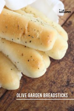 bread sticks with herbs on them sitting on top of a wooden table in front of the words olive garden breadsticks