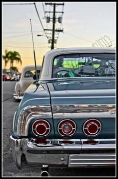 an old car parked on the side of the road with other cars in the background