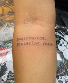 a person with a tattoo on their arm that says masterpiece, mastering peace in black ink