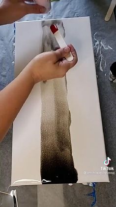 someone is using a brush to paint the bottom part of a piece of paper with black and white ink