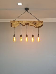 five light bulbs hanging from a wooden beam in a room with white walls and ceiling