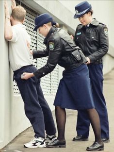 two police officers helping a boy put on his uniform