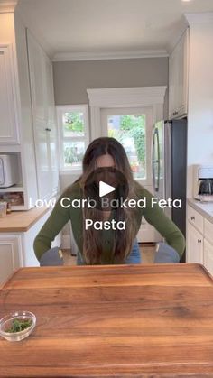 a woman standing in front of a kitchen counter with food on top of it and the caption low carb baked feta pasta