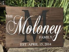 a wooden sign that says the moloney family on it in front of some flowers