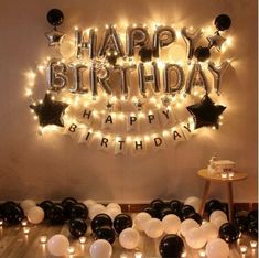 a birthday party with black and white balloons, stars and lights on the wall above it