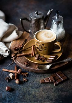 a cup of cappuccino on a plate with cinnamons and cloves