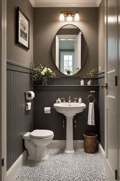 a white toilet sitting next to a sink in a bathroom under a round mirror on the wall